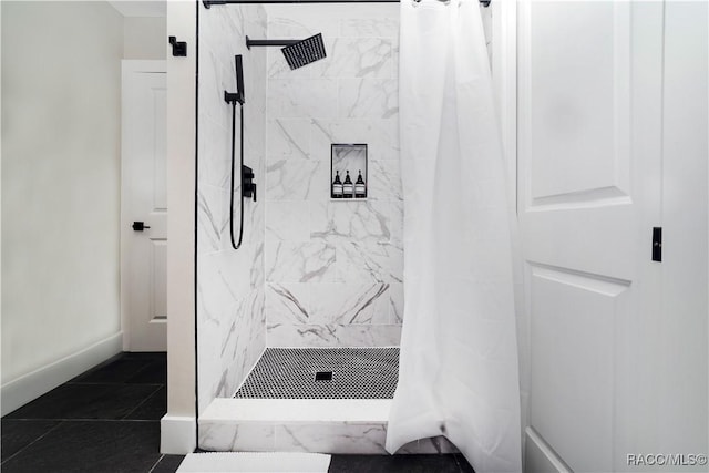 bathroom featuring tiled shower and baseboards