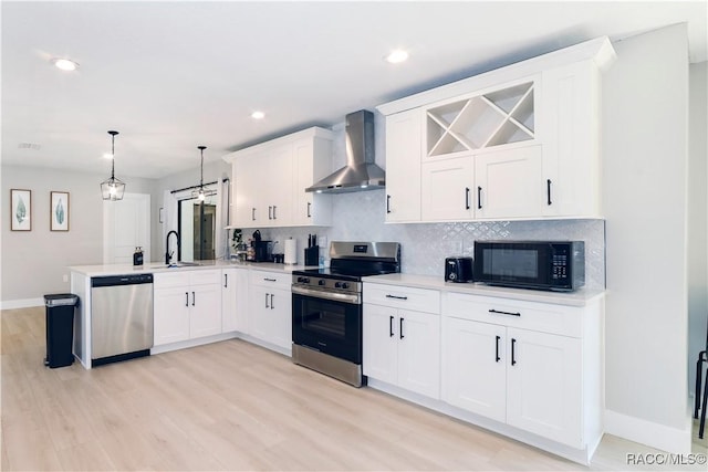 kitchen with tasteful backsplash, wall chimney range hood, a peninsula, light countertops, and appliances with stainless steel finishes