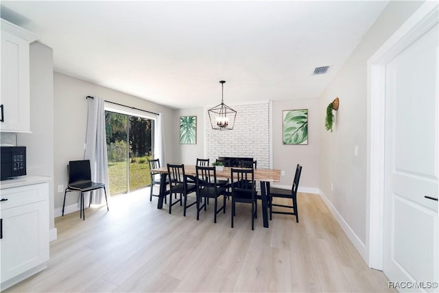dining area featuring light wood-type flooring, baseboards, visible vents, and a notable chandelier
