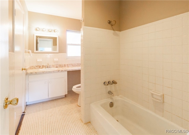 full bathroom with tile patterned floors, toilet, vanity, tile walls, and tiled shower / bath