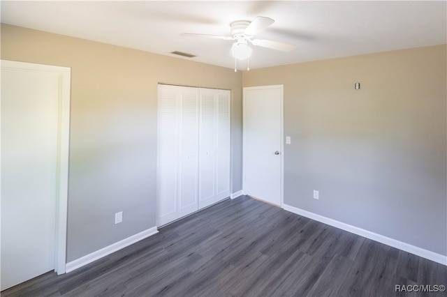 unfurnished bedroom with ceiling fan, dark hardwood / wood-style floors, and a closet