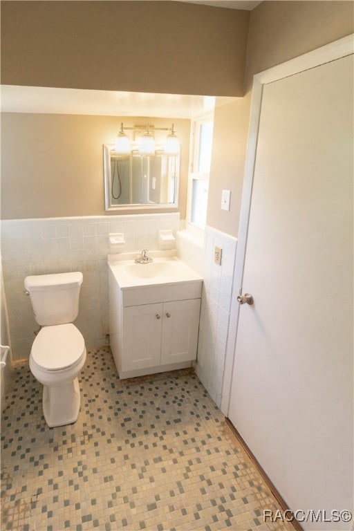 bathroom with vanity, toilet, and tile walls