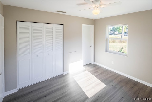 unfurnished bedroom with a closet, ceiling fan, and dark wood-type flooring