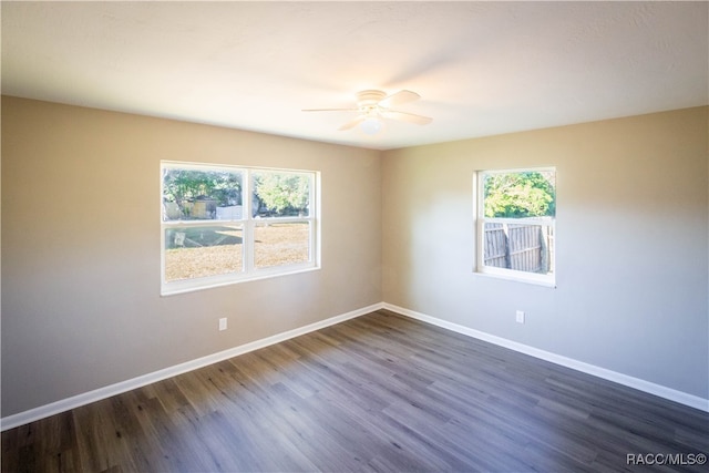 empty room with dark hardwood / wood-style flooring, ceiling fan, and a healthy amount of sunlight