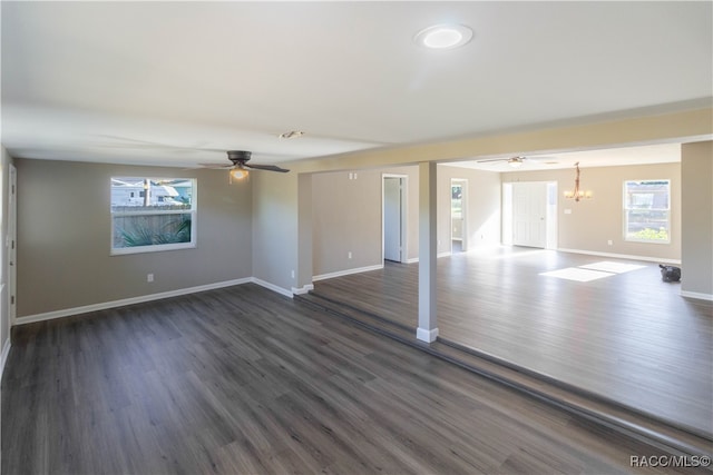 spare room with ceiling fan with notable chandelier and dark hardwood / wood-style floors