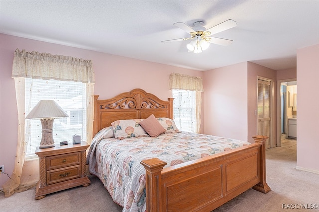 bedroom featuring ensuite bathroom, a textured ceiling, light colored carpet, ceiling fan, and a closet