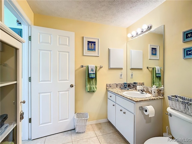 bathroom featuring toilet, vanity, a textured ceiling, and tile patterned floors