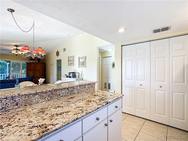 kitchen featuring white cabinets, ceiling fan with notable chandelier, vaulted ceiling, light stone countertops, and light tile patterned floors