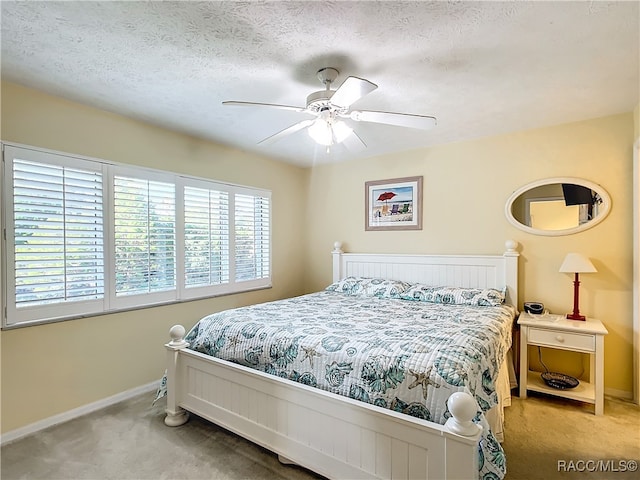 bedroom featuring a textured ceiling, light colored carpet, and ceiling fan