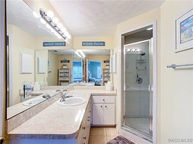 bathroom featuring tile patterned flooring, vanity, a textured ceiling, and walk in shower