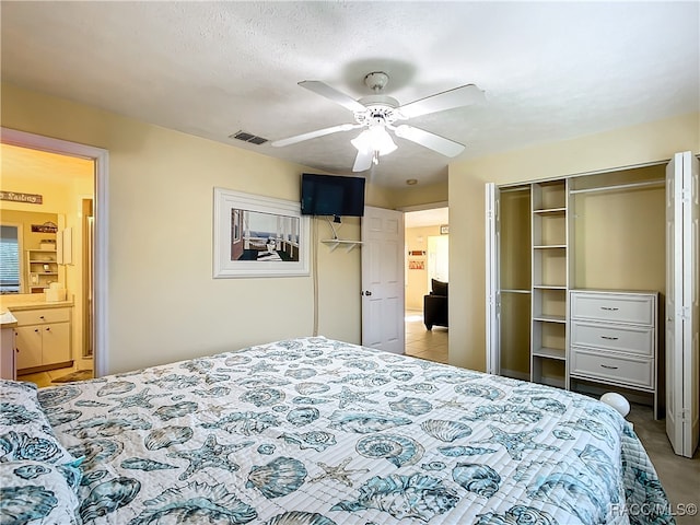 bedroom featuring connected bathroom, ceiling fan, a closet, and a textured ceiling