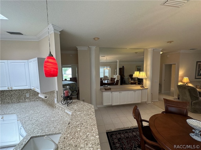 kitchen with decorative columns, white cabinetry, light tile patterned floors, and ornamental molding