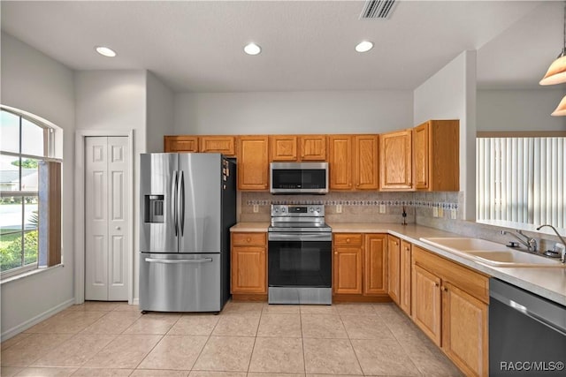 kitchen featuring stainless steel appliances, tasteful backsplash, sink, hanging light fixtures, and light tile patterned floors