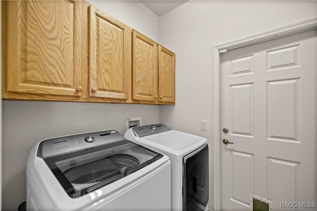 washroom with cabinets and washer and clothes dryer