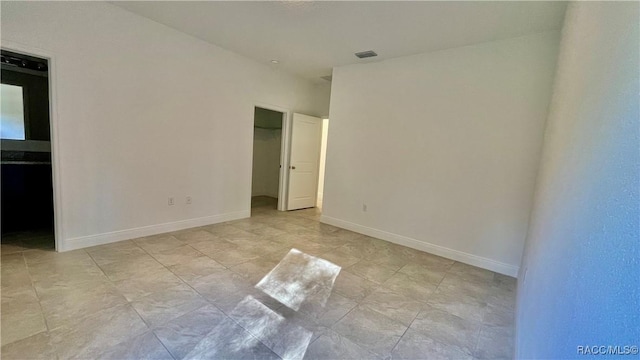 unfurnished bedroom with a spacious closet, visible vents, and baseboards