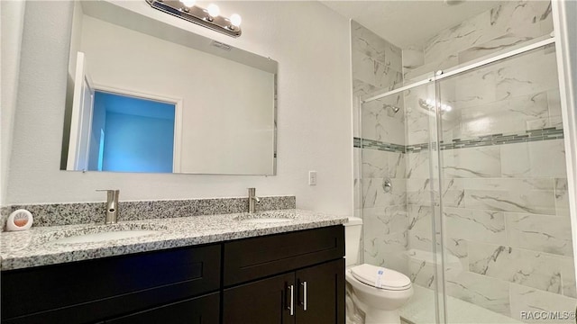 full bathroom with toilet, a sink, a marble finish shower, and double vanity