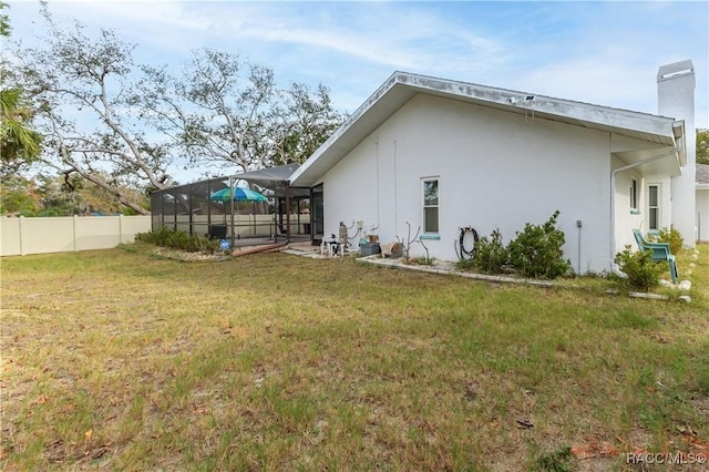 rear view of property with a yard and glass enclosure