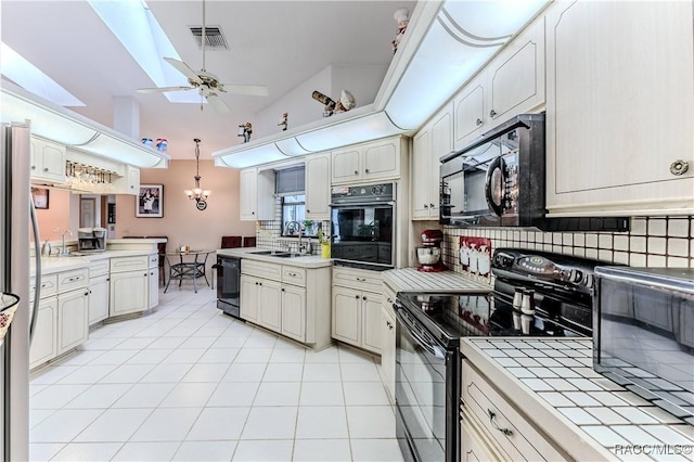 kitchen featuring ceiling fan with notable chandelier, decorative light fixtures, sink, light tile patterned floors, and black appliances