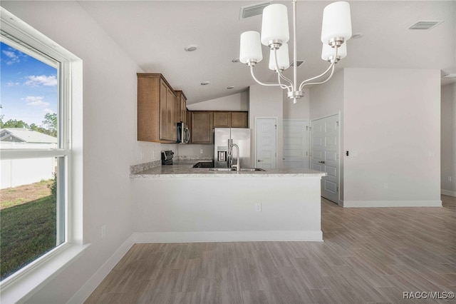 kitchen with sink, stainless steel appliances, decorative light fixtures, vaulted ceiling, and kitchen peninsula