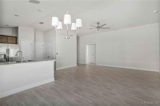 kitchen featuring sink, light hardwood / wood-style flooring, ceiling fan with notable chandelier, stainless steel fridge with ice dispenser, and decorative light fixtures