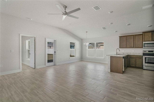 kitchen with appliances with stainless steel finishes, ceiling fan with notable chandelier, sink, hanging light fixtures, and kitchen peninsula