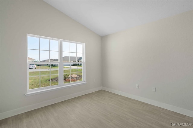 spare room with lofted ceiling and light hardwood / wood-style flooring