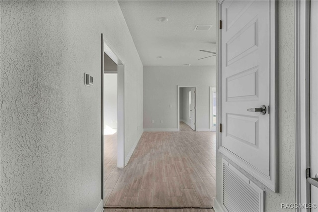 hall featuring light hardwood / wood-style flooring and a textured ceiling