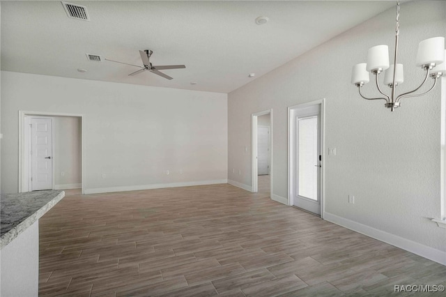 spare room featuring wood-type flooring and ceiling fan with notable chandelier