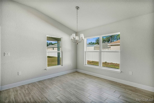 unfurnished dining area with an inviting chandelier, light hardwood / wood-style flooring, and lofted ceiling