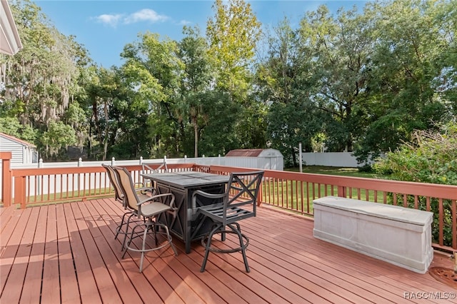 wooden deck featuring a lawn and a storage unit