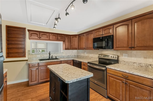 kitchen with sink, a center island, tasteful backsplash, light hardwood / wood-style flooring, and black appliances