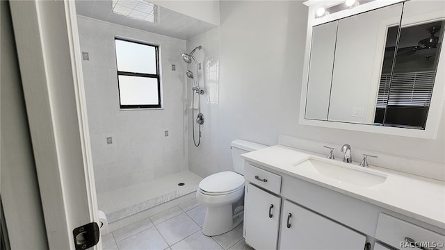 bathroom with tiled shower, tile patterned floors, vanity, and toilet