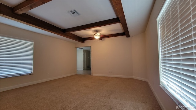 unfurnished room with ceiling fan, beamed ceiling, and light colored carpet