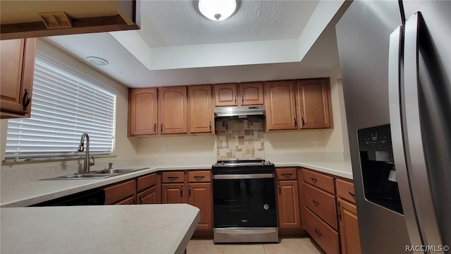 kitchen featuring sink, stainless steel appliances, a raised ceiling, decorative backsplash, and light tile patterned floors