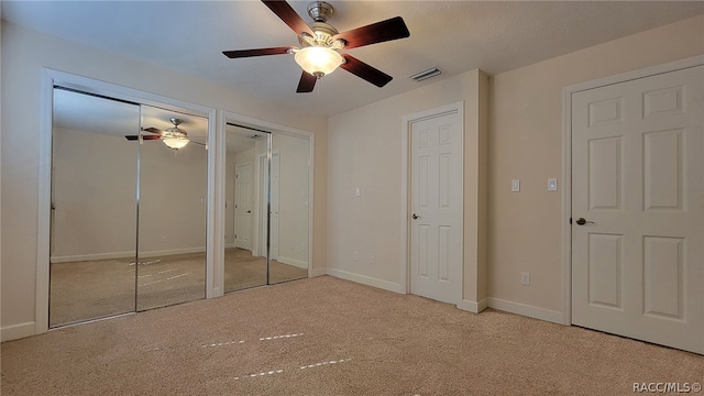 unfurnished bedroom with multiple closets, ceiling fan, and light carpet