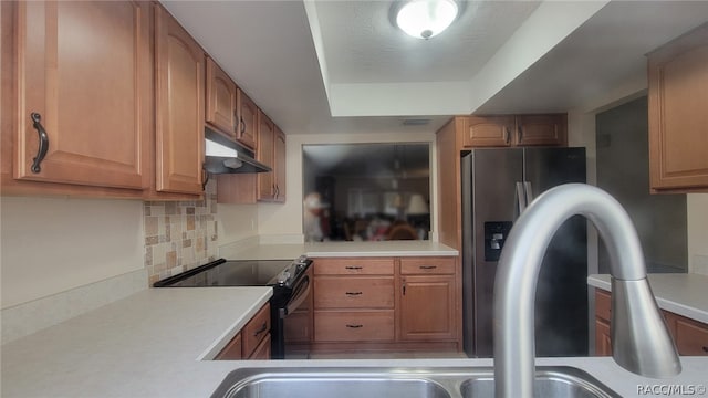 kitchen featuring tasteful backsplash, black range with electric stovetop, a tray ceiling, and stainless steel refrigerator with ice dispenser