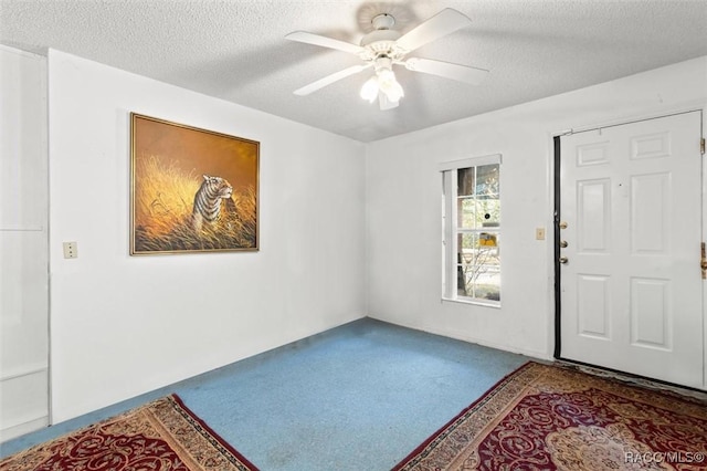 carpeted foyer featuring ceiling fan and a textured ceiling