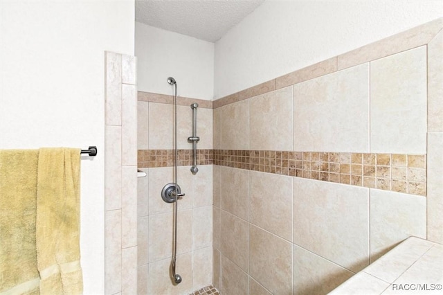 bathroom with a tile shower and a textured ceiling