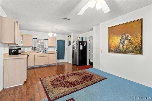 kitchen featuring light brown cabinets, a textured ceiling, stainless steel refrigerator, and sink