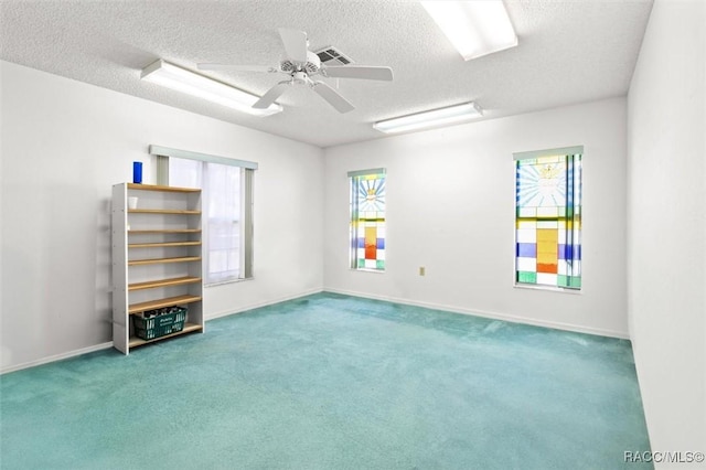 carpeted spare room featuring ceiling fan and a textured ceiling