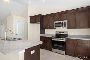 kitchen with sink, stainless steel appliances, dark brown cabinetry, and an island with sink