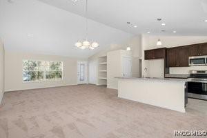 kitchen with light carpet, appliances with stainless steel finishes, vaulted ceiling, and dark brown cabinets