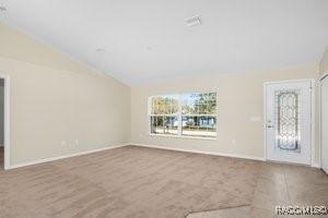 unfurnished living room with carpet floors and lofted ceiling