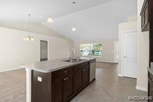 kitchen featuring dark brown cabinetry, sink, stainless steel dishwasher, pendant lighting, and a center island with sink