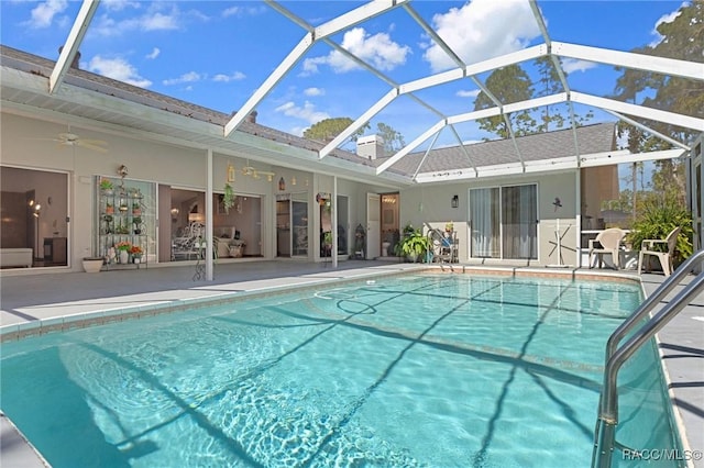 outdoor pool featuring glass enclosure, a ceiling fan, and a patio