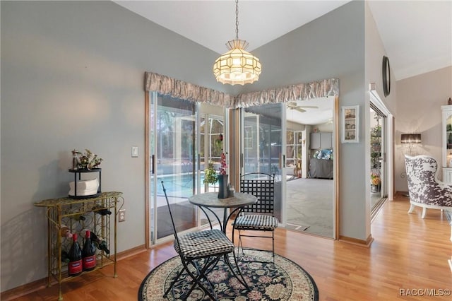 dining area with light wood-type flooring, baseboards, a ceiling fan, and vaulted ceiling