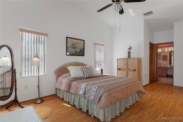 bedroom with visible vents, connected bathroom, light wood-style floors, and vaulted ceiling