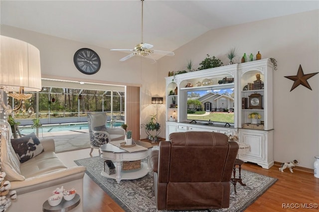 living area featuring light wood-style flooring, lofted ceiling, baseboards, and ceiling fan