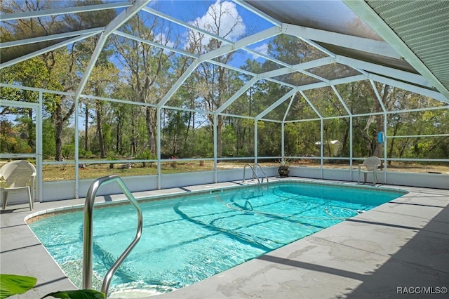 outdoor pool featuring glass enclosure and a patio