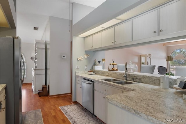 kitchen featuring light wood-type flooring, visible vents, a sink, stainless steel appliances, and light countertops